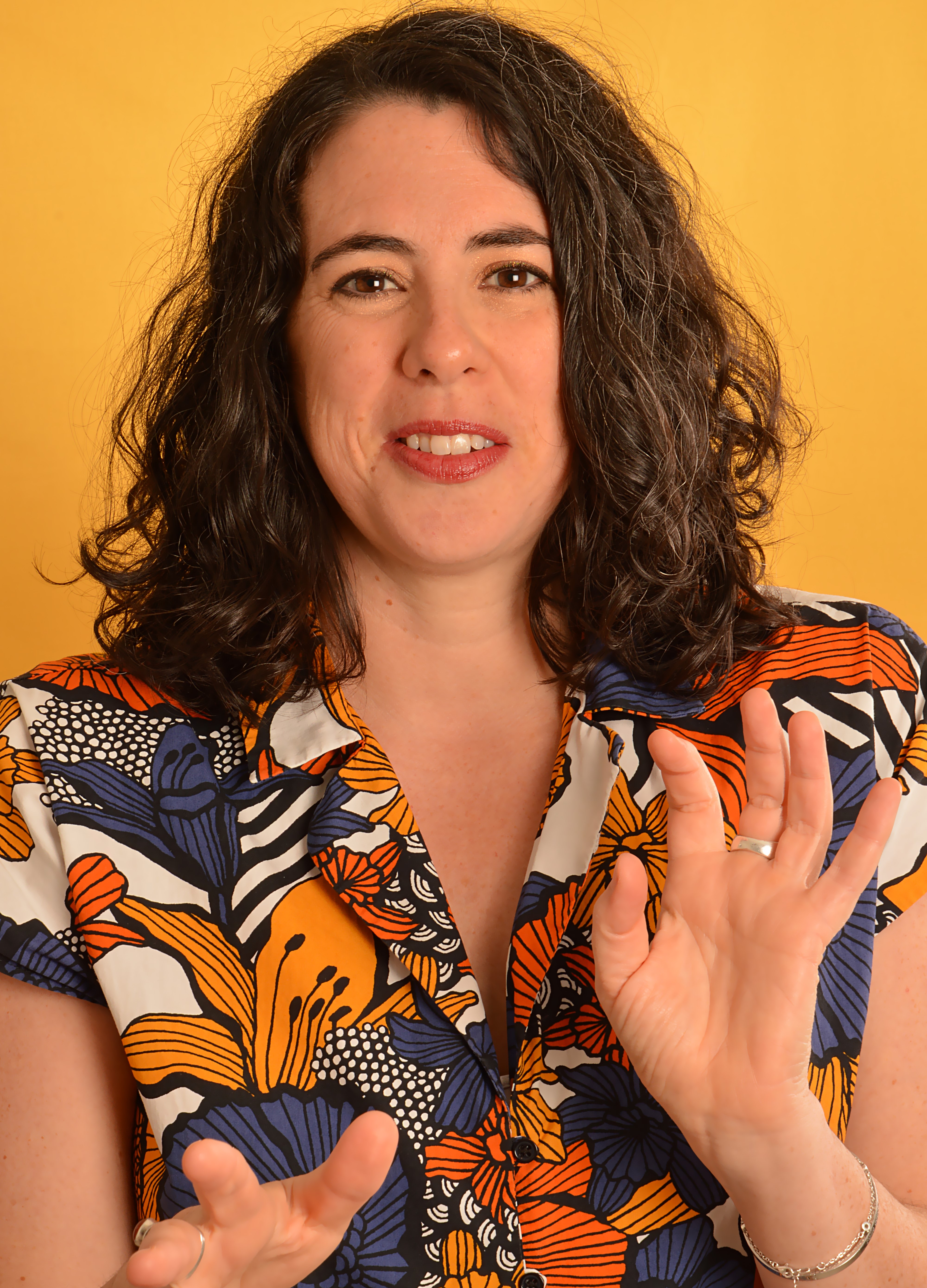 Clémence Fouquet - Consultante RH Diversité et Inclusion. Portrait de face de la tête à la taille, Clémence Fouquet sourit et porte une robe à fond blanc avec des grandes fleurs bleues et oranges